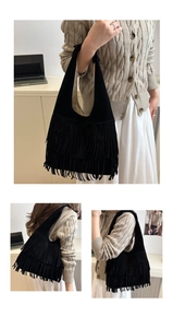 Dettaglio di una borsa hobo in camoscio nero con lunghe frange e struttura a mezzaluna