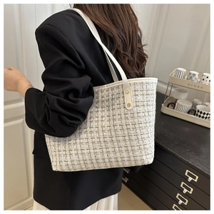 Close-up detail of beige tweed tote bag with leather handles and gold rivet accents