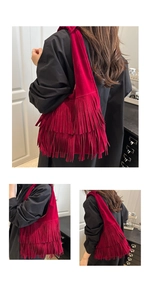 Dettaglio della borsa a spalla in camoscio rosso con frange su un cappotto nero