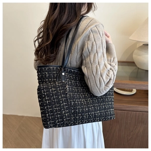Detail of black and gold tweed tote bag with metal zipper and luxury woven texture