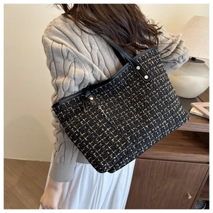 Detail of black tweed tote bag with gold thread accents and leather shoulder strap