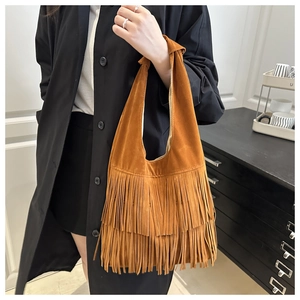 Dettaglio della borsa in pelle scamosciata color caramello con frange boho e manico annodato