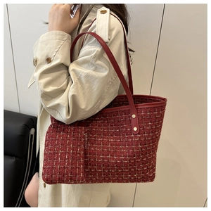 Detail of red tweed tote bag with leather trim and hanging zipper pouch shown on model