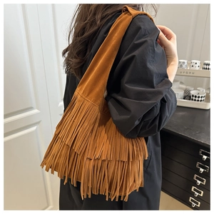 Close-up of brown suede tassel shoulder bag showing boho fringes and soft texture