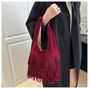 Detail of burgundy suede tote bag featuring multi-layer fringe tassels and a shoulder strap