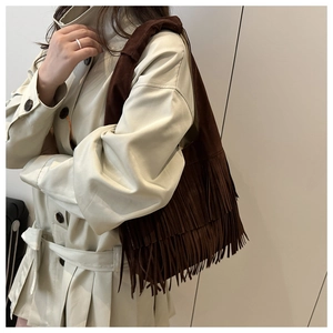 Detail of bohemian dark brown suede fringe tote bag styled on a beige trench coat