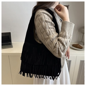 Dettaglio della borsa tote bohémien in camoscio nero con lunghe frange portata a spalla