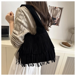 Dettaglio di una borsa a spalla in camoscio nero vintage con lunghe nappe boho