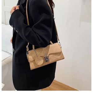 Close-up of the khaki leather shoulder bag showing the silver lock and fashion tag