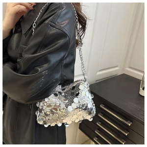 Sac à bandoulière en paillettes argentées avec chaîne en métal sur une veste en cuir