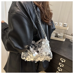 Close-up of silver sequin shoulder bag with metallic chain strap worn over black leather jacket