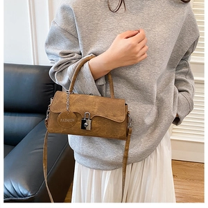 Detail of tan suede crossbody bag with vintage metal lock and Fashion metal tag