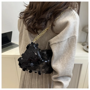 Détail d'un sac à bandoulière à paillettes noires avec chaîne dorée sur un mannequin