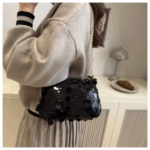 Détail du sac à bandoulière chic en paillettes noires avec chaîne dorée et texture brillante