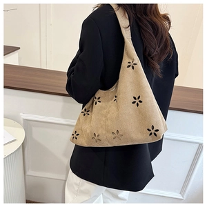 Détail du sac hobo en daim beige avec motifs floraux découpés au laser et large bandoulière