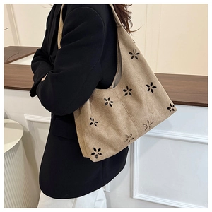 Détail de motifs floraux découpés au laser sur un grand sac cabas en daim kaki élégant
