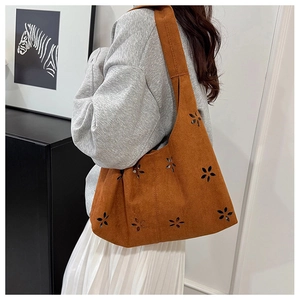 Détail d'un sac cabas en daim marron avec des motifs floraux découpés au laser élégants