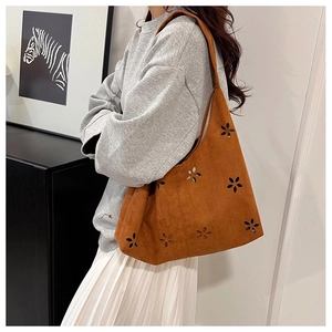 Sac hobo en daim marron avec motifs floraux découpés au laser porté par le mannequin