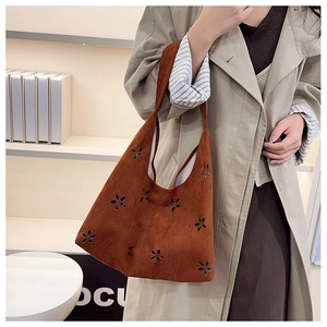 Détail de fleurs découpées au laser sur un sac cabas rétro en daim marron avec sangle