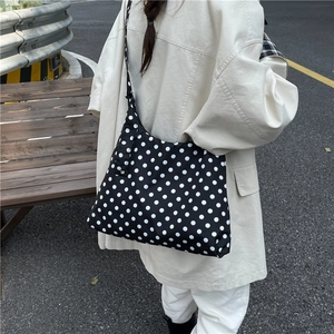 Stylish large capacity black and white polka dot crossbody bag worn in a street setting