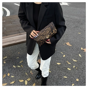 Close-up of leopard print envelope clutch with a gold buckle on an outdoor street background