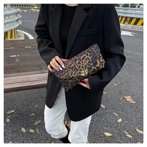 Detail of leopard print envelope clutch with golden heart buckle held by model