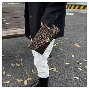 Detail of leopard print envelope clutch featuring a gold leaf-shaped metal clasp
