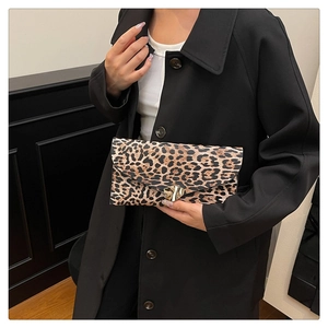 Detail of leopard print envelope clutch featuring a gold heart clasp and PU leather texture