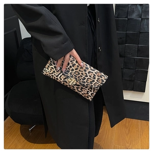 Detailed view of leopard print clutch with golden triangular metal buckle on black coat