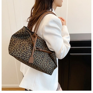 Detail of leopard print tote bag with brown leather straps worn with a white blazer
