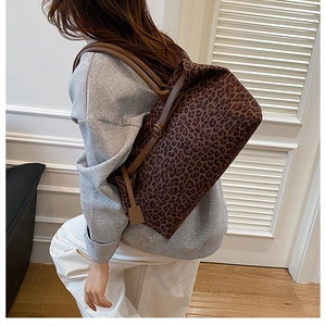 Detailed view of leopard print tote bag with brown leather straps worn over the shoulder