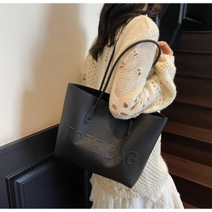 Detailed side view of the black matte tote bag showing the embossed logo and shoulder fit