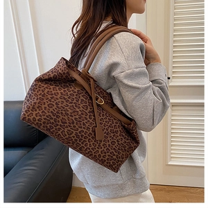 Detail of leopard print tote bag with brown leather handles and gold metal accents