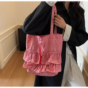 Detail of red gingham tote bag featuring ruffles and adjustable drawstring closure
