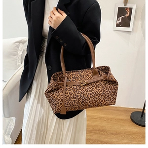 Detail of leopard print tote bag featuring brown leather handles and premium fabric texture