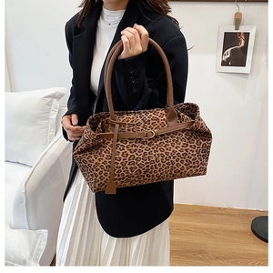 Close-up of leopard print tote bag featuring brown straps and elegant gold buckle detail