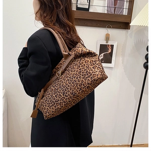 Detail of leopard print faux suede tote bag with brown leather handles and adjustable straps