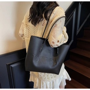 Detail of black leather tote bag featuring a high-quality 3D embossed text design