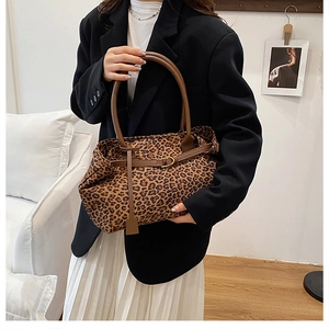 Detail of leopard print tote bag featuring brown leather handles and premium hardware