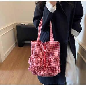 Detail of red and white checkered tote bag featuring tiered ruffles and drawstring closure