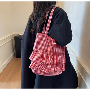 Detail of red gingham tote bag featuring tiered ruffles and adjustable drawstring closure