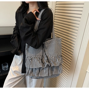 Detail view of the black and white checkered tote bag with elegant ruffled hem design