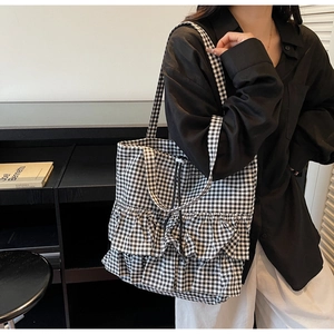 Detail of checkered canvas tote bag featuring ruffled layers and drawstring closure design