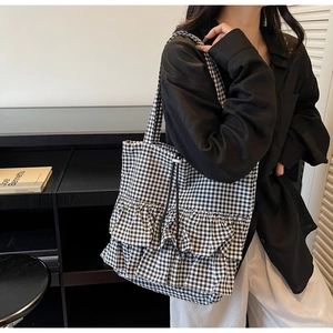 Detail of checkered tote bag with ruffled layers and black drawstring closure