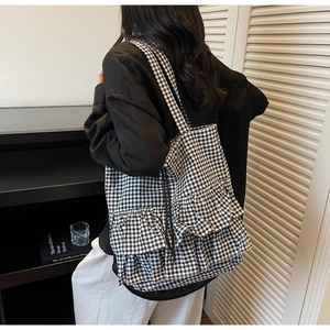 Detail of black and white gingham tote bag with large decorative ruffles and long shoulder strap