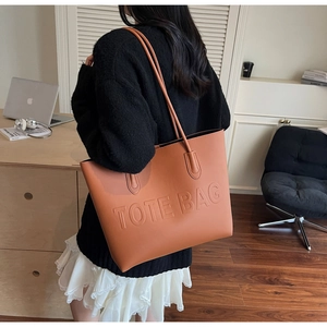Detailed close-up of textured brown tote bag featuring embossed TOTE BAG text detail