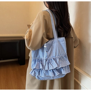 Detail of blue gingham tote bag showing ruffled edges and drawstring closure for women