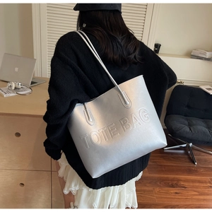 Silver large capacity tote bag with embossed TOTE BAG text shown on shoulder