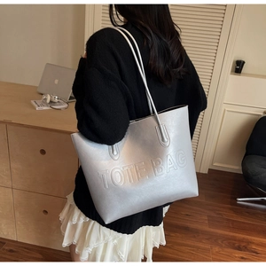 Silver large capacity tote bag with embossed lettering shown in a lifestyle daily setting