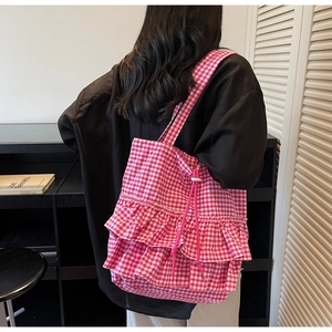 Back view of model wearing pink gingham tote bag with ruffled layers and drawstring